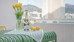 A table with a bottle of champagne, two glasses, and lemons on a striped tablecloth, overlooking a city and mountains. - Daegu Hyeonpung Prana Hotel (Daegu)