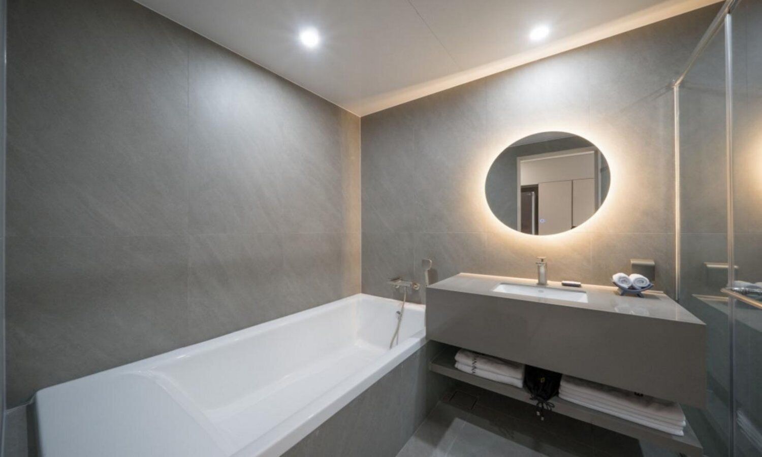 A modern bathroom with a bathtub, a vanity with a mirror, and a towel rack.