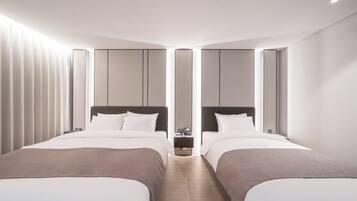 A modern hotel room with two beds, a nightstand, and a wall-mounted phone.