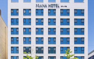 Un edificio de varios pisos con un letrero que dice 'PRANA HOTEL' y caracteres coreanos.