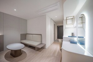 Een moderne, minimalistisch ingerichte kamer met een ronde tafel, een bank en een ingebouwde kaptafel met spiegels.
