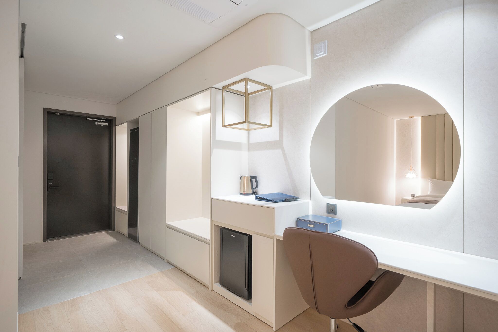 A modern hotel room with a desk, chair, and a large mirror.