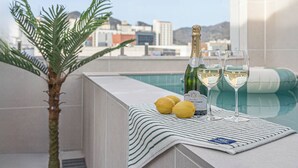 A rooftop pool area with a bottle of champagne, two glasses, and lemons on a towel. - Daegu Hyeonpung Prana Hotel (Daegu)