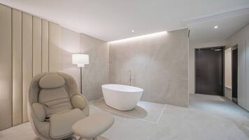 Une salle de bain moderne avec une baignoire sur pieds, un fauteuil massant et un lampadaire.