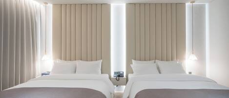 A hotel room with two beds, a bedside table with a phone, and a window with curtains.