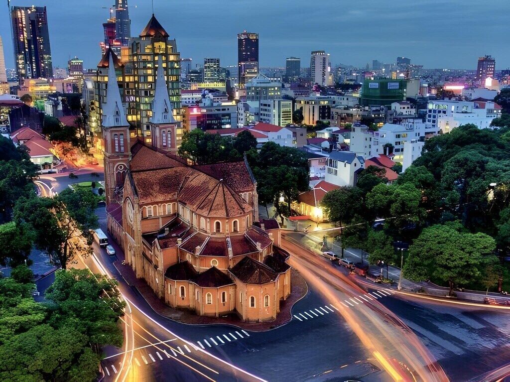 En historisk kyrka med en central kupol och flera mindre kupoler, omgiven av en stadsbild med moderna byggnader.