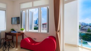 Una sala de estar moderna con un sofá rojo, un escritorio con una computadora y un televisor en la pared.