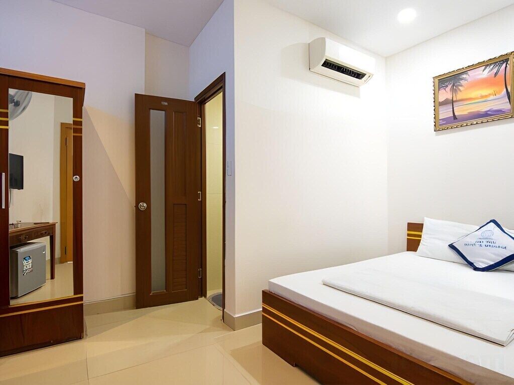 Habitación de hotel con cama, armario, aire acondicionado y un cuadro en la pared.
