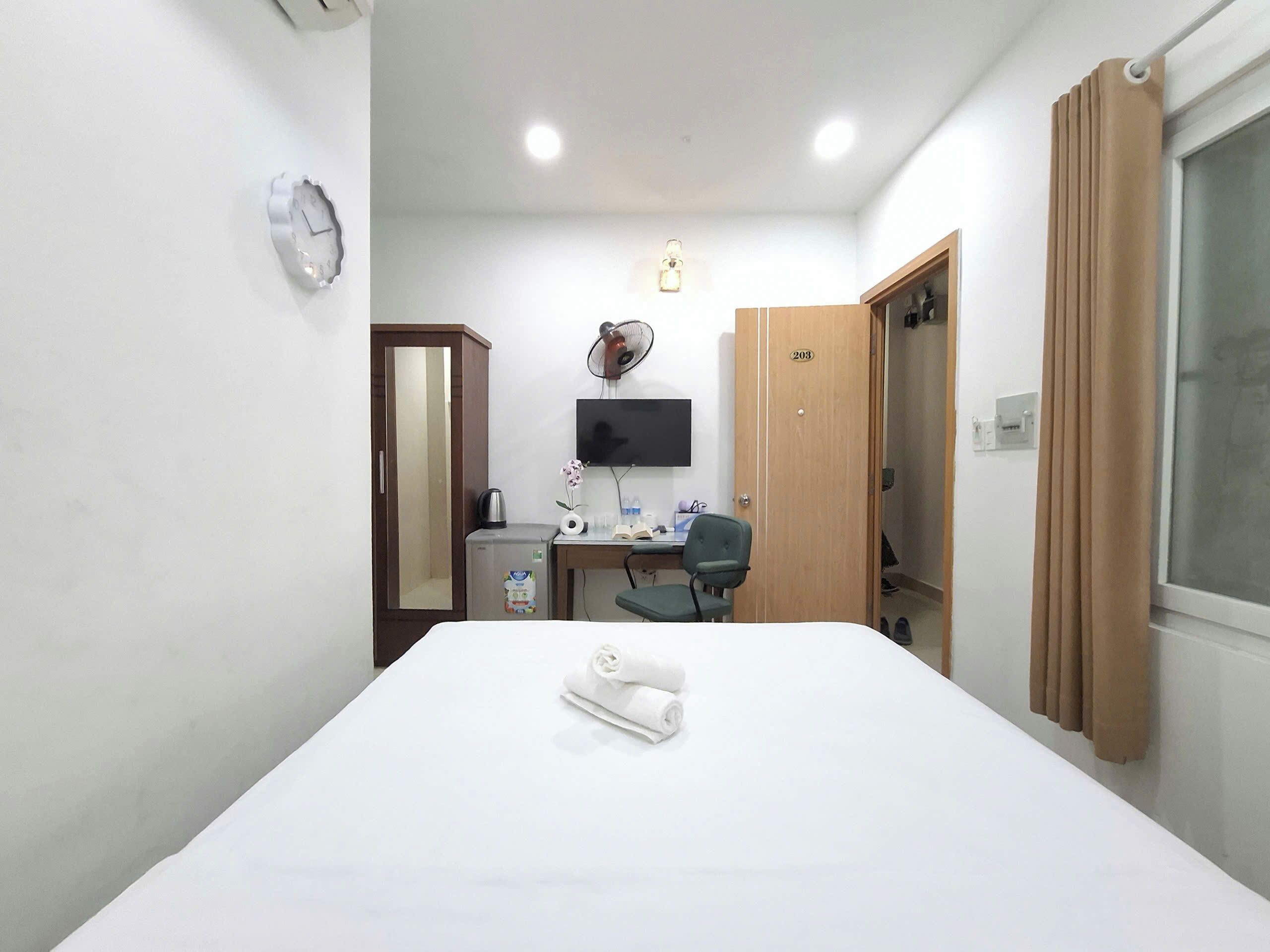 Ein Hotelzimmer mit Bett, Schreibtisch, Stuhl, Fernseher, Kleiderschrank und Spiegel.
