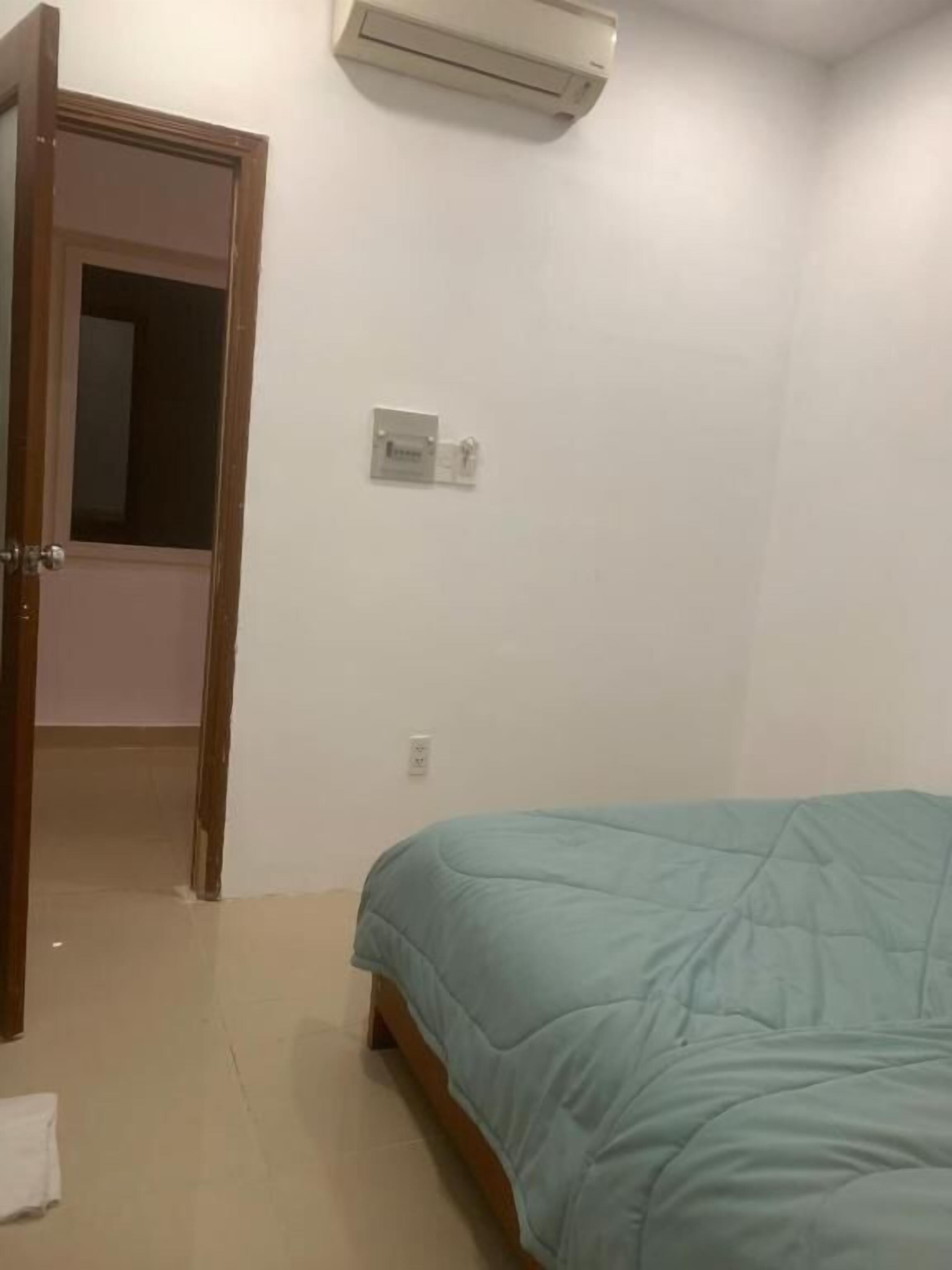Une chambre à coucher comprenant un lit, un climatiseur, une porte et une prise électrique.