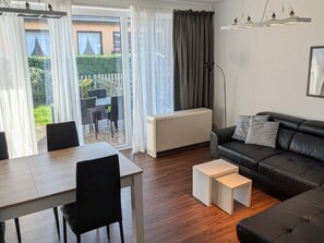 Ein modernes Wohnzimmer mit einer schwarzen Ledersofa, einem weißen Couchtisch und einem Essbereich mit einem Holztisch und Stühlen.