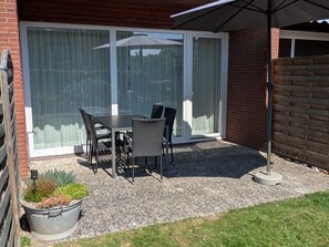 A patio with a table and chairs, a potted plant, and a sliding glass door. - "Mour" Vacation Apartment - "Mour" townhouse with a terrace, 2 stories, sleeps 4 (Dahme)