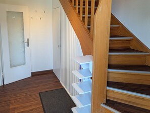 Eine Treppe mit Holzboden und weißen Geländern, die zu einer Zwischenebene mit einem weißen Regal führt.
