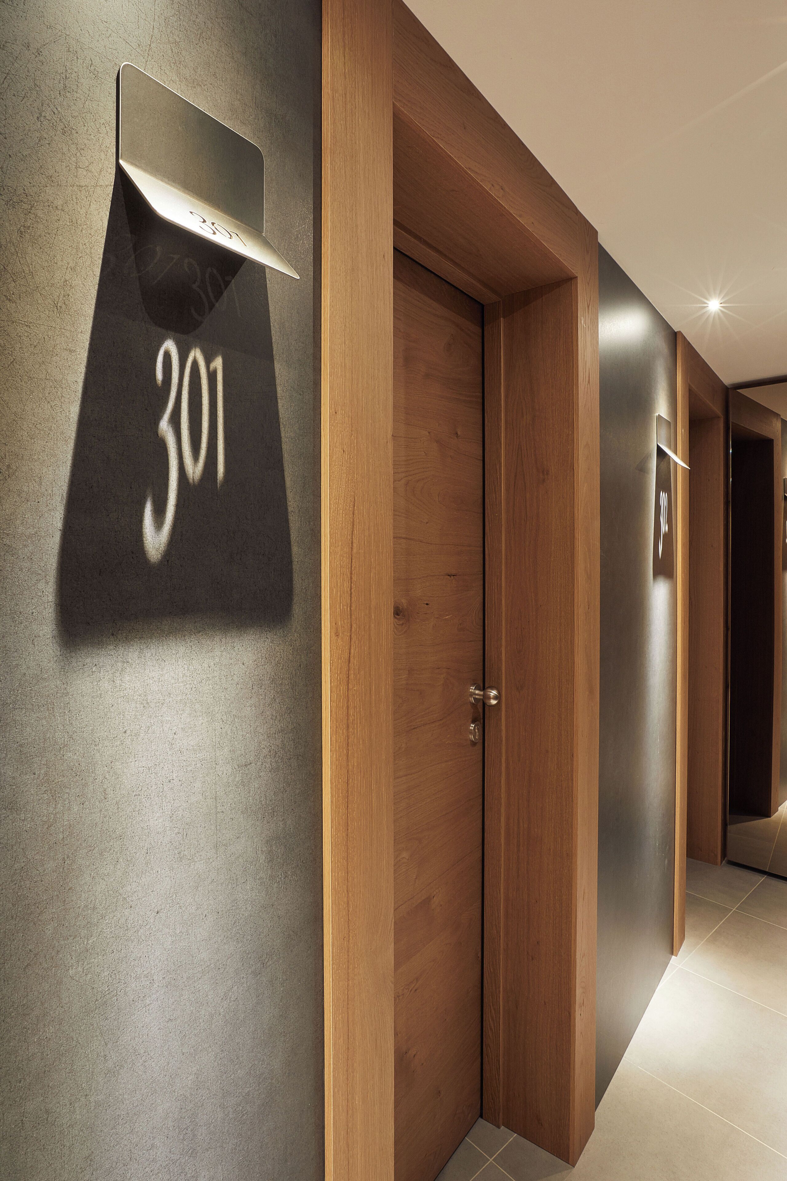 Un couloir moderne avec des portes en bois et un panneau indiquant le numéro de la pièce : 301.