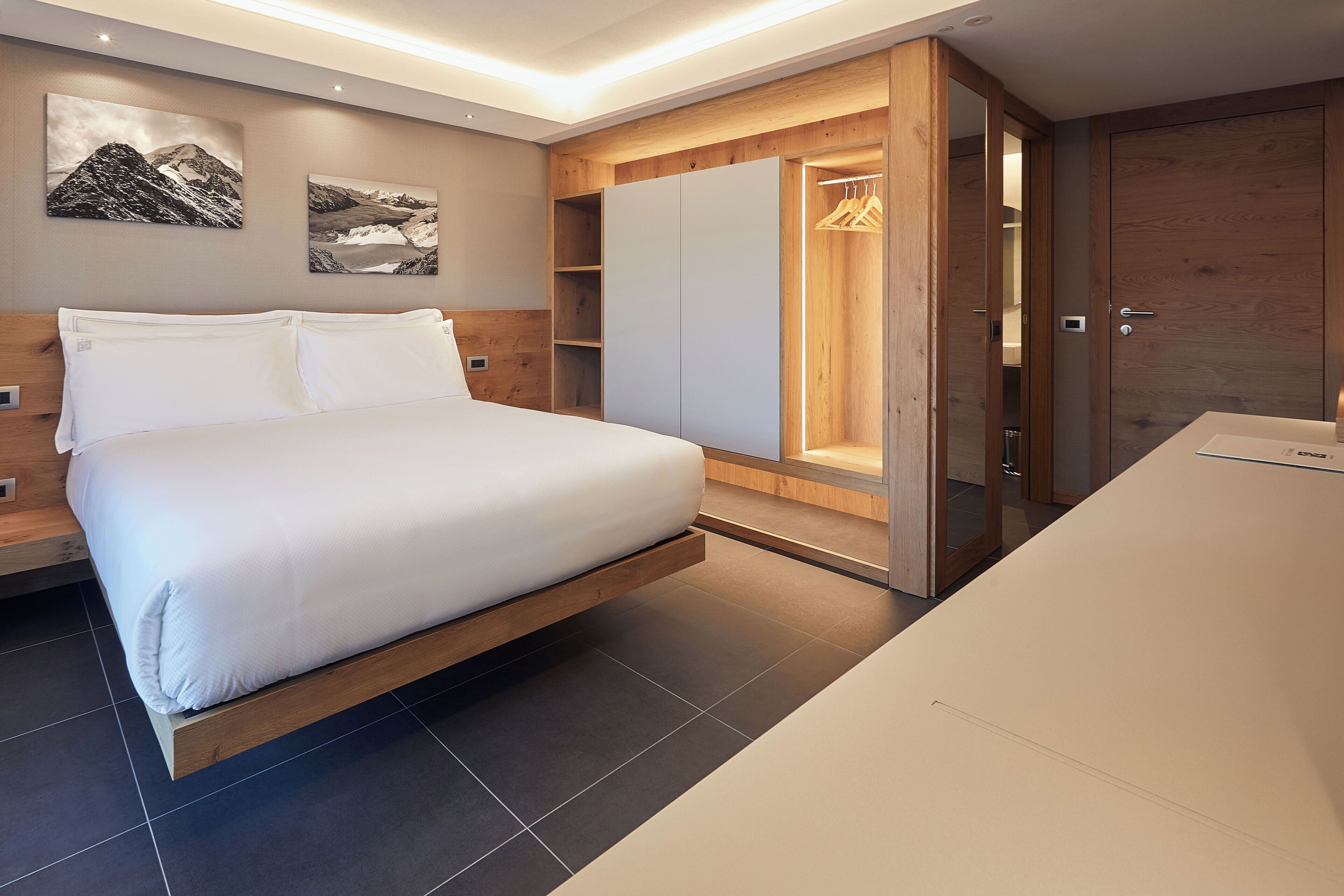 A modern bedroom with a bed, wooden wardrobe, and a built-in closet with a hanging rack.
