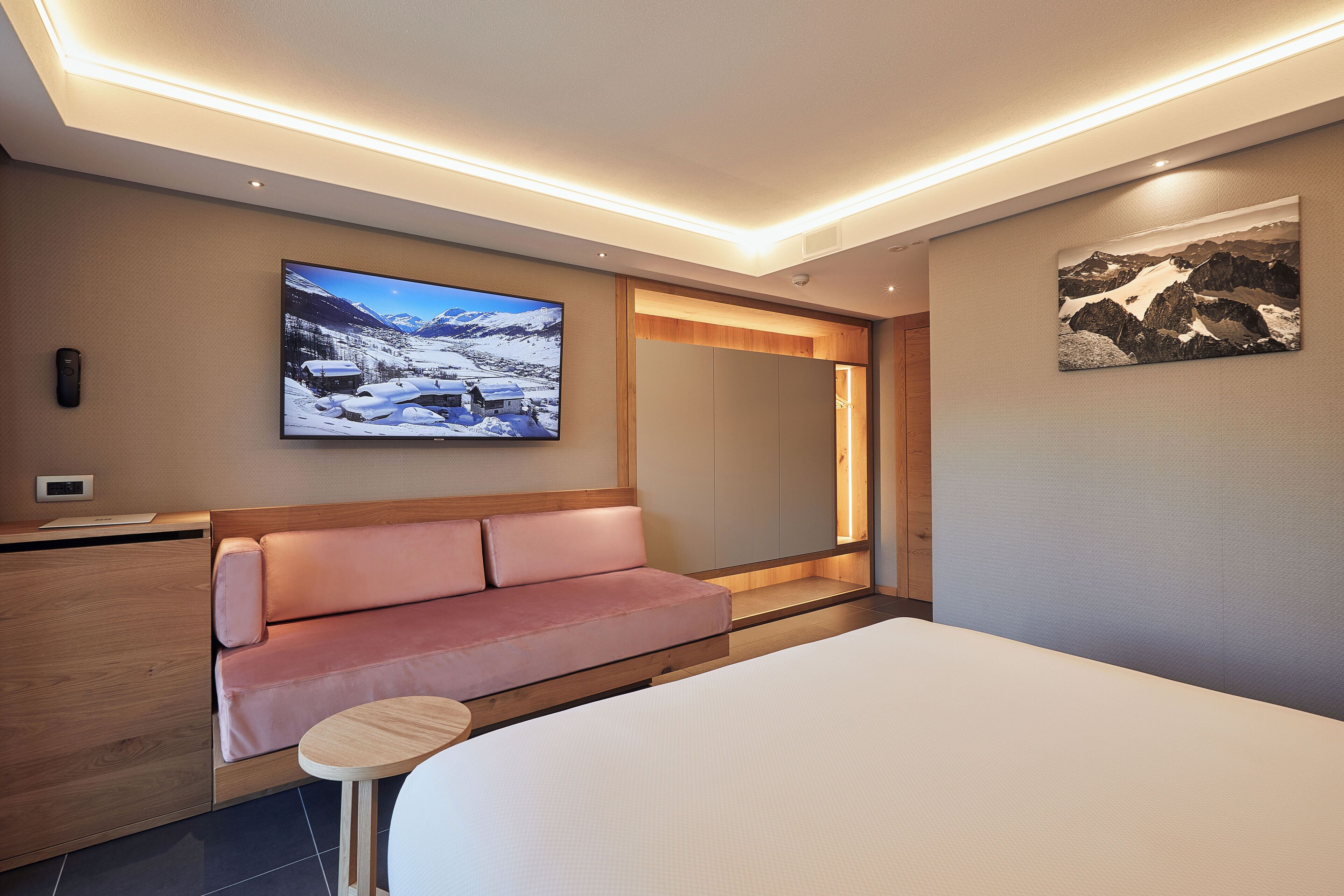 Et moderne hotelværelse med seng, sofa, lille bord, fjernsyn og et maleri på væggen.