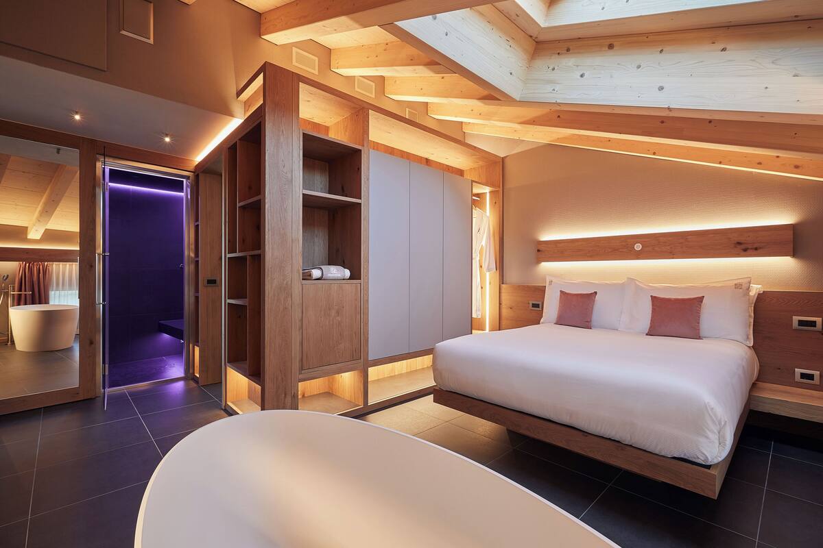 A modern bedroom with a large bed, built-in wardrobe, and a skylight.