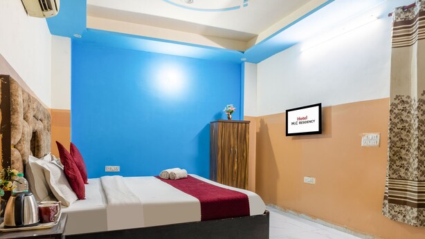 A hotel room with a bed, a desk with a kettle, a fruit bowl, and a ceiling fan. - Hotel M.C Residence (New Delhi)
