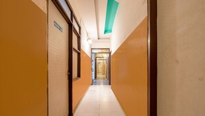 A hotel corridor with a sign reading "ROOM NO 101" on the left, leading to a door at the end. - Hotel M.C Residence (New Delhi)