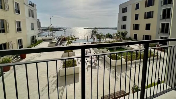 Ein Balkon mit Blick auf ein Gewässer und eine Brücke, umgeben von modernen Gebäuden.