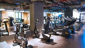 Ein Fitnessstudio mit verschiedenen Cardiogeräten, Krafttrainingsgeräten und einer Spiegelwand.