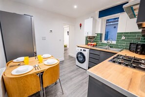 Une cuisine compacte équipée d’un lave-linge intégré, d’une table à manger avec des chaises et d’une cuisinière.