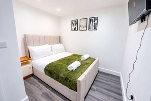 A hotel room with a bed, a nightstand, a green throw blanket, and three framed artworks on the wall. - Cardiff 2-Bed Flat | Equipped Kitchen & Private Entrance (Cardiff)