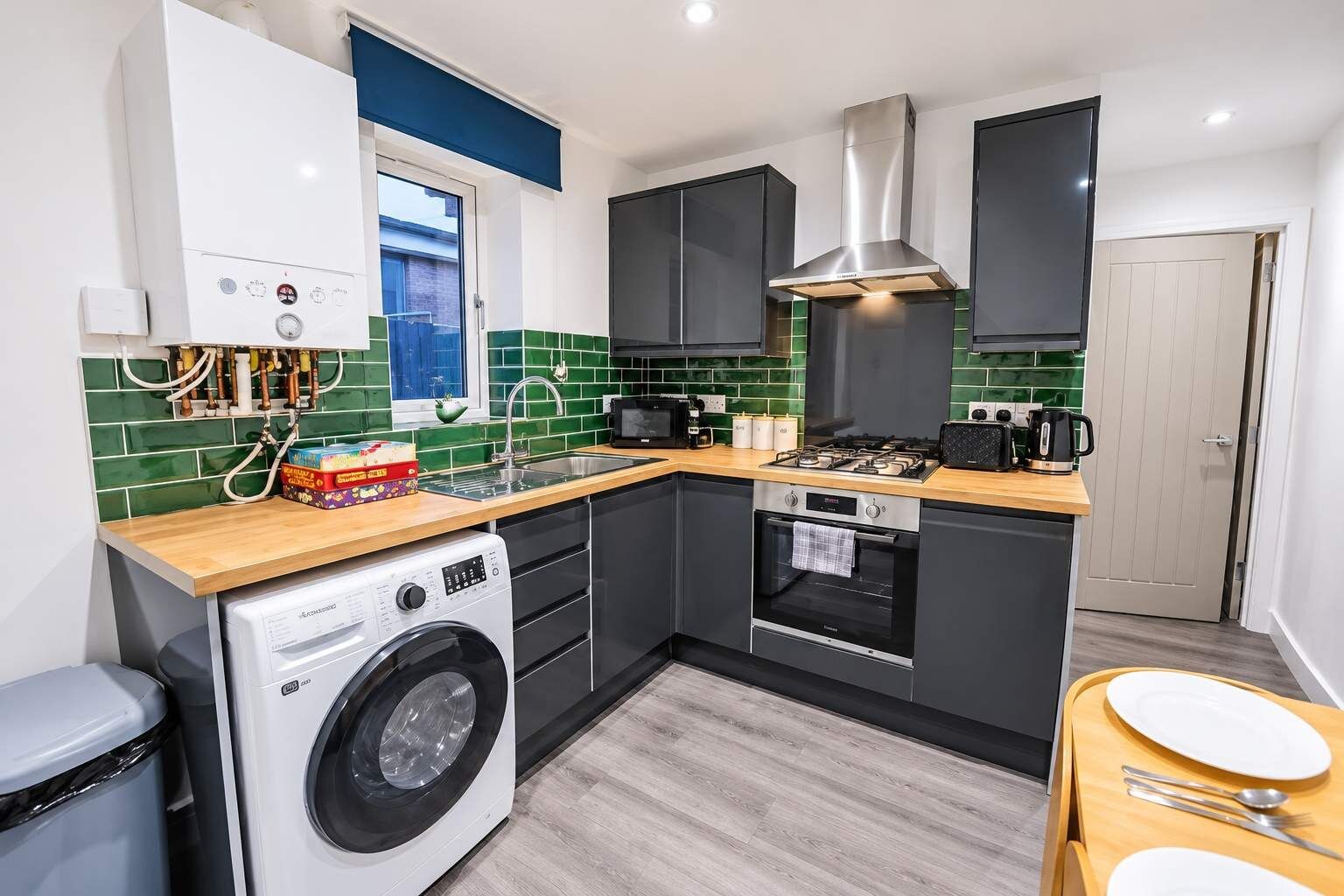 A compact kitchen with a washing machine, a stove, and a microwave.