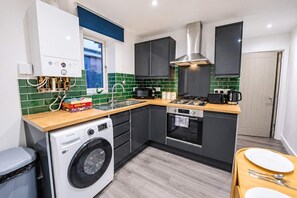 Une cuisine compacte équipée d’un lave-linge, d’une cuisinière et d’un four à micro-ondes.