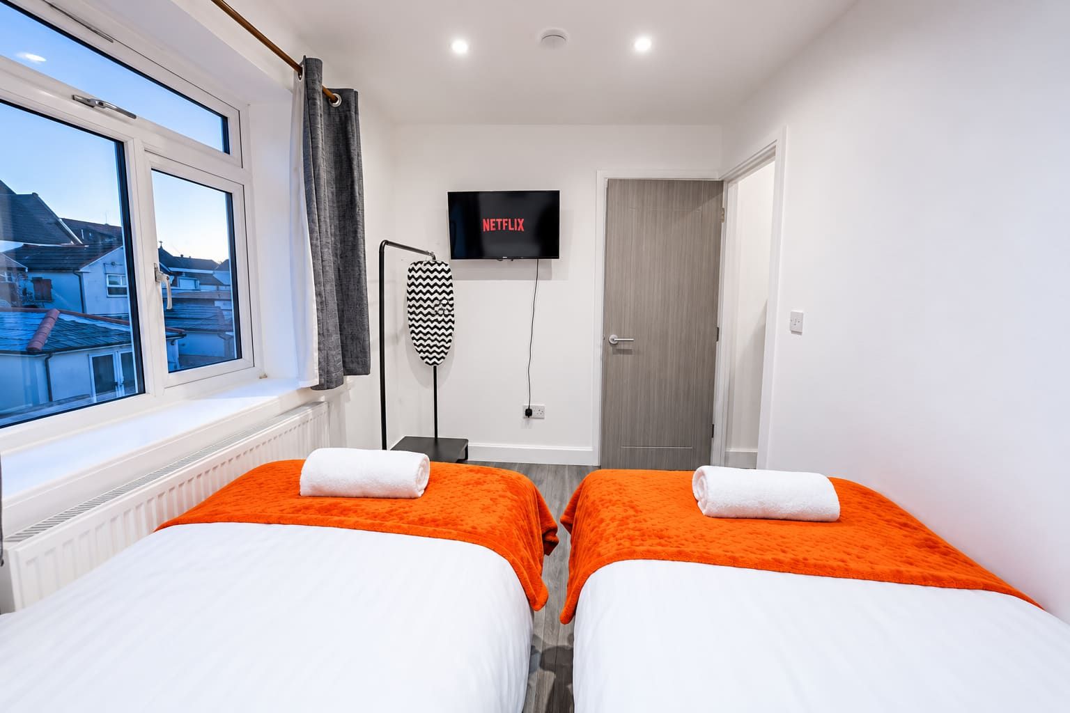 A hotel room with two beds, a TV, and a view of the outside.