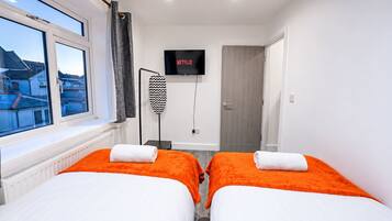 A hotel room with two beds, a TV, and a view of the outside.