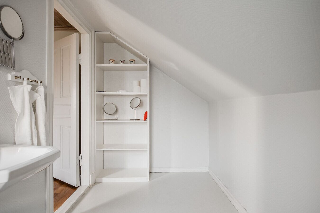 Un baño blanco y minimalista con lavabo blanco, espejo y toallero.