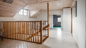 A room with a wooden slatted partition, a staircase, and a view of another room with a green floor. - Cozy Country Home in Quiet Töreboda (Töreboda)
