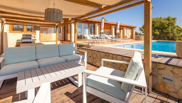 Un espacio al aire libre techado con piscina, sillas de descanso, un sofá y una parrilla.