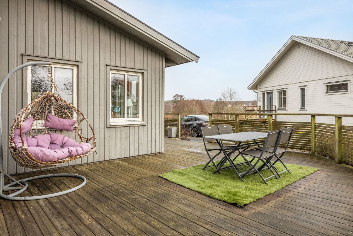 Eine Holzterrasse mit einer Hängematte und einem Tisch mit Stühlen.