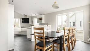 Eine moderne Küche mit weißen Schränken, einer dunklen Arbeitsplatte und einem Essbereich mit Holzkästen und einem schwarzen Tisch.