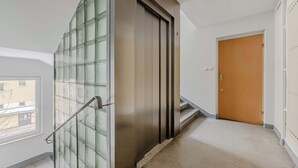 Un interior moderno con un separador de vidrio, una puerta de madera y una escalera.