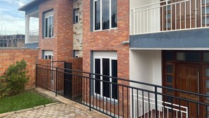 Een woonhuis met twee verdiepingen, gevel van baksteen, witte details en een balkon met metalen hekwerk.