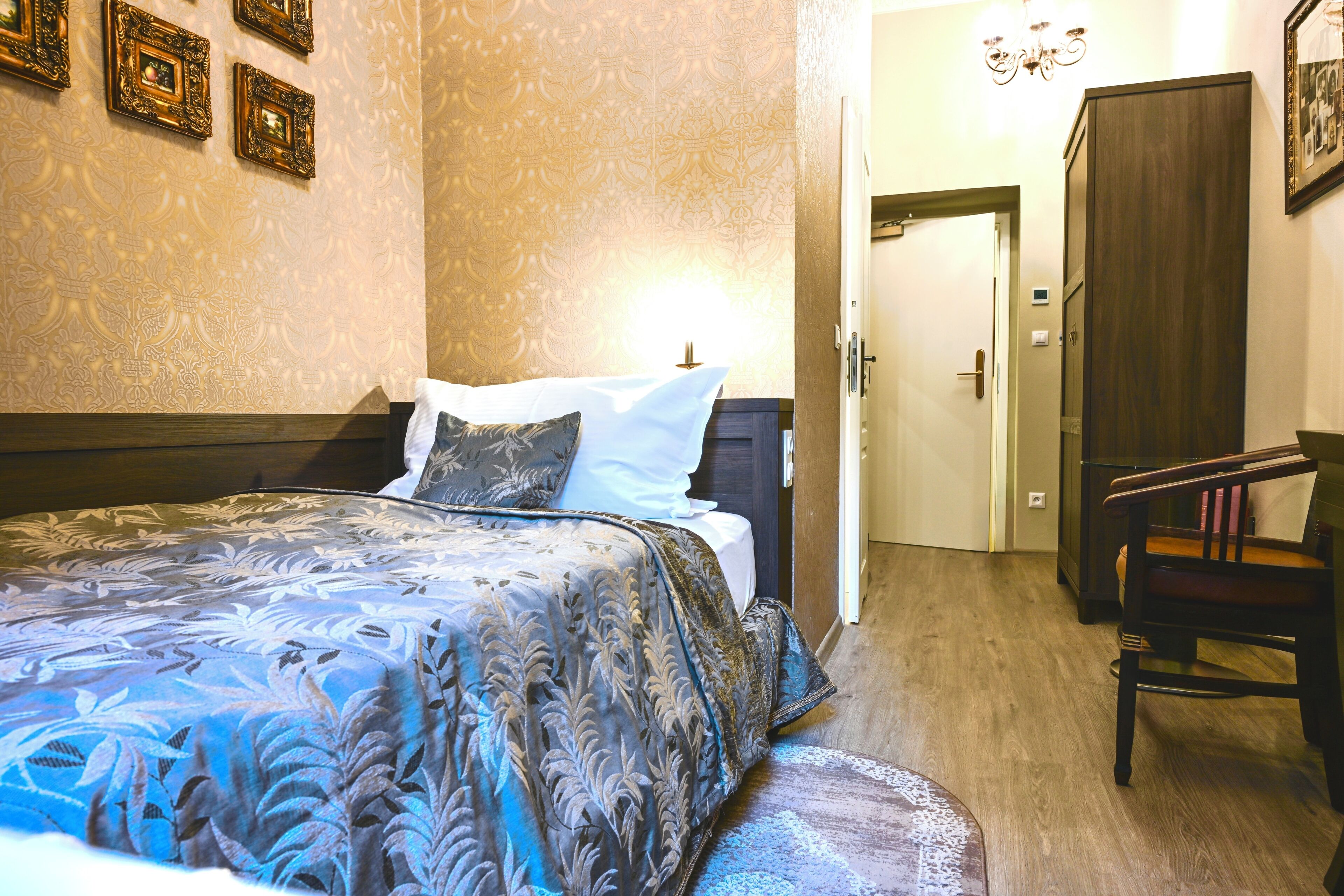 A bedroom with a bed, a chair, a wardrobe, and a door.