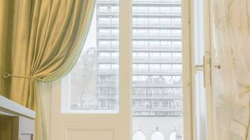 A room with a large window, a door, and a view of buildings outside.