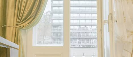 A room with a large window, a door, and a view of buildings outside.