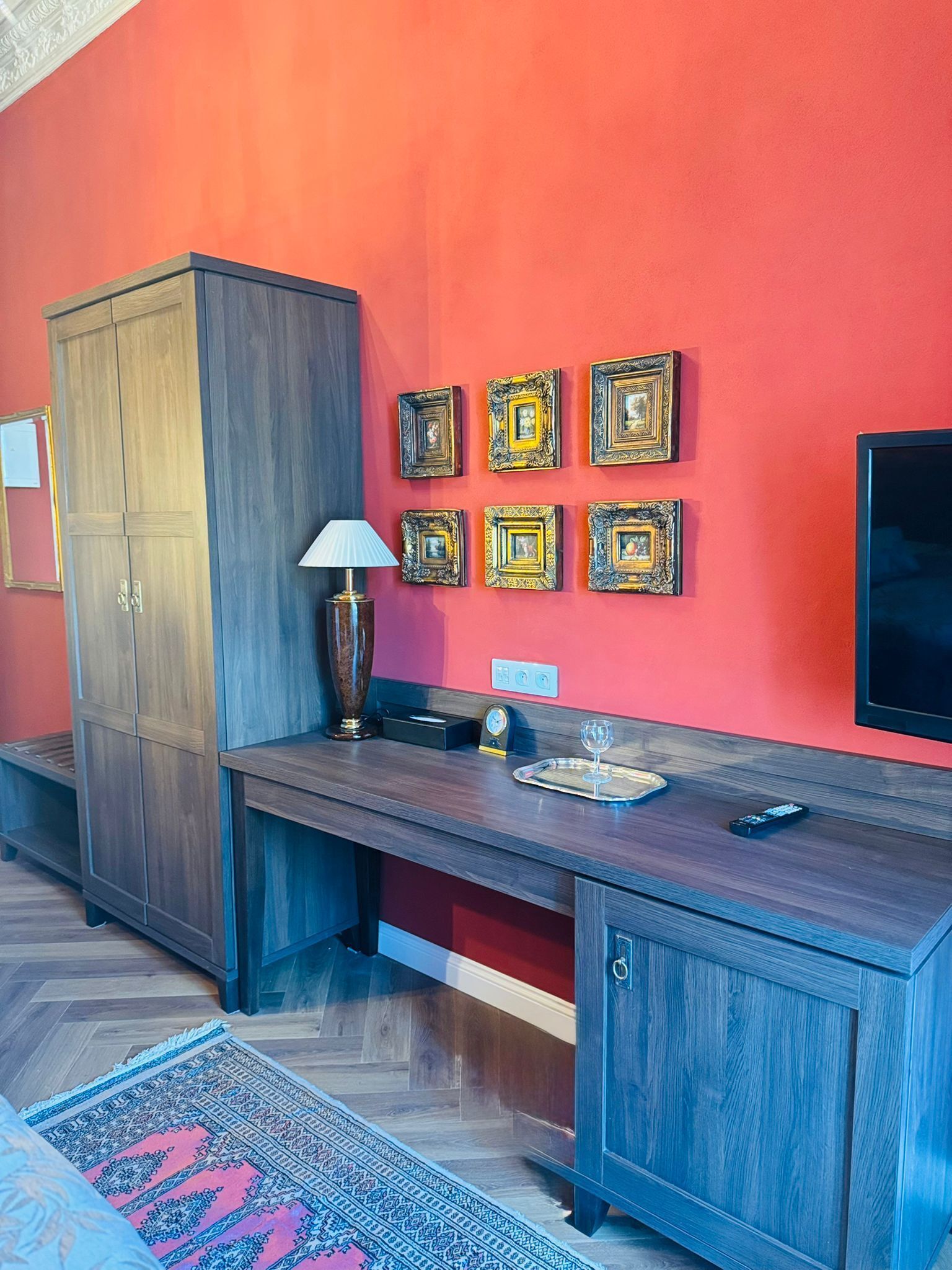 A modern kitchen with a wooden cabinet, a TV, and decorative frames on the wall.