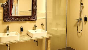 A bathroom with two sinks, a large mirror, and a glass-enclosed shower.