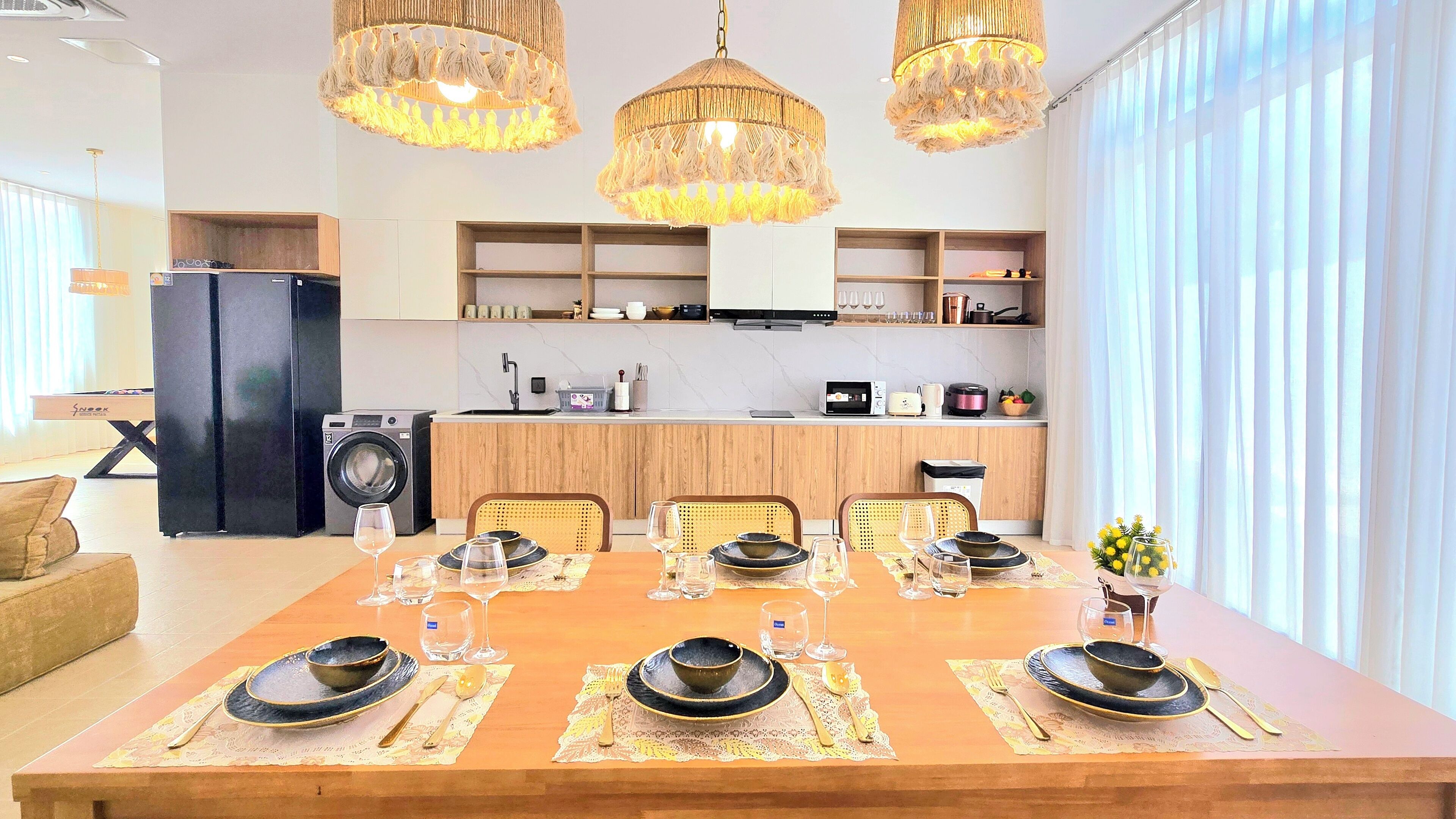 Uma cozinha moderna com armários de madeira, forno embutido e área de jantar com mesa de madeira posta para seis pessoas.