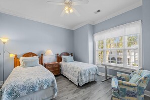 A bedroom with two beds, a nightstand, a chair, and a window with blinds. - Golf Vacation 4 Bedroom Fairway View (Pawleys Island)