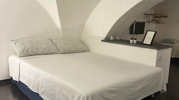 A modern bedroom with a bed, a dresser, and a small table with decorative items. - Independent apartment two minutes from the Duomo (Catania)