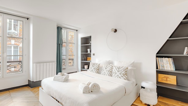 Camera da letto moderna con un letto grande, un armadio a muro, un angolo salotto e vista da una finestra.