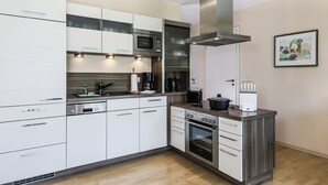 Eine moderne Küche mit weißen Schränken, Edelstahlgeräten und einem eingebauten Backofen.