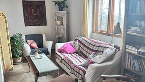 A cozy living room with a sofa, armchair, wooden coffee table, and a bookshelf. - Ayur Garden (Lanckorona)