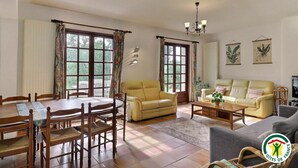 Ein geräumiges Wohnzimmer mit Esstisch, zwei Sofas und einer Deckenleuchte.